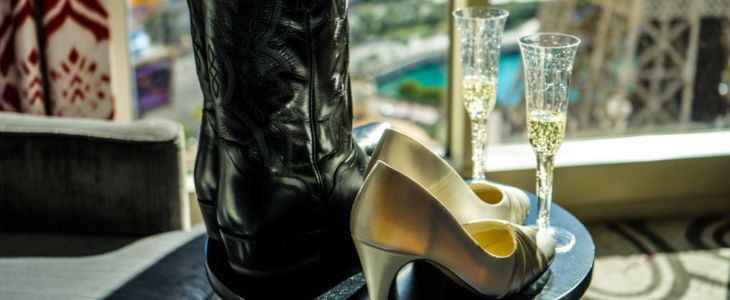 a pair of cowboy boots next to a pair of gold high heels and two champagne glasses