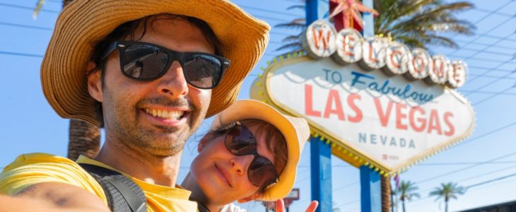 a couple posing for a photo in front of the Las Vegas sign