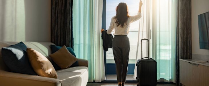 a woman on a business trip looks out of the window of her hotel room