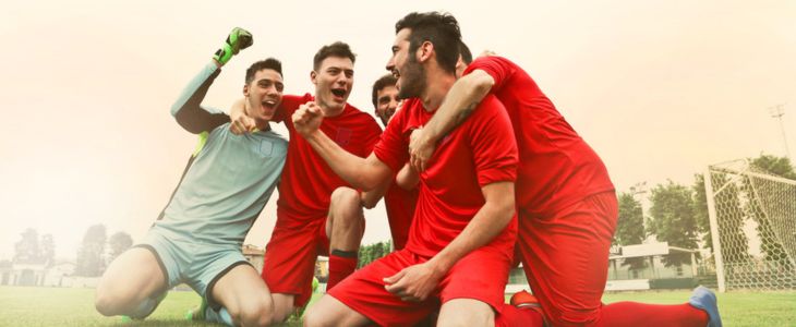 A soccer team cheering after scoring a goal.