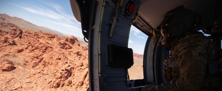 An Airman looks out of the window of a helicopter in the desert around Las Vegas