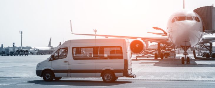 A small shuttle bus parked on the runway at an airport