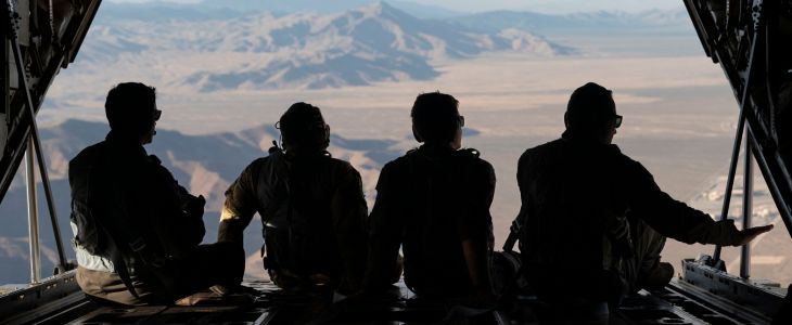 A line of airmen sitting at the back of a helicopter as it flys over the desert near Las Vegas